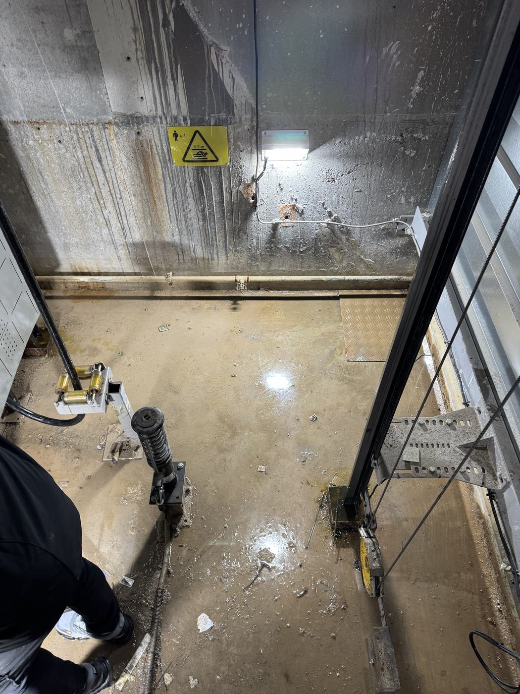 Water staining down the walls of a lift pit with water sitting on the pit floor